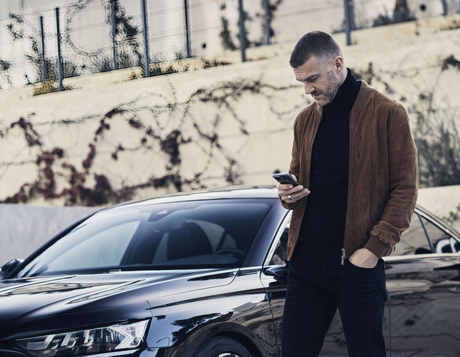 Чоловік дивиться на екран смартфона на вулиці перед DS 9, що стоїть поруч