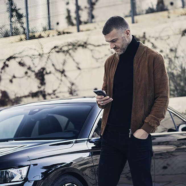 Чоловік дивиться на екран смартфона на вулиці перед DS 9, що стоїть поруч